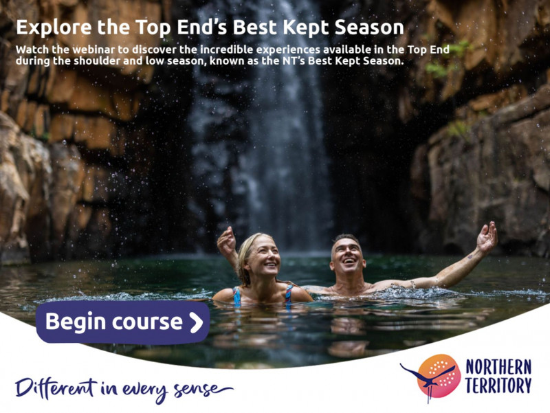 Man and woman swimming at the base of a waterfall